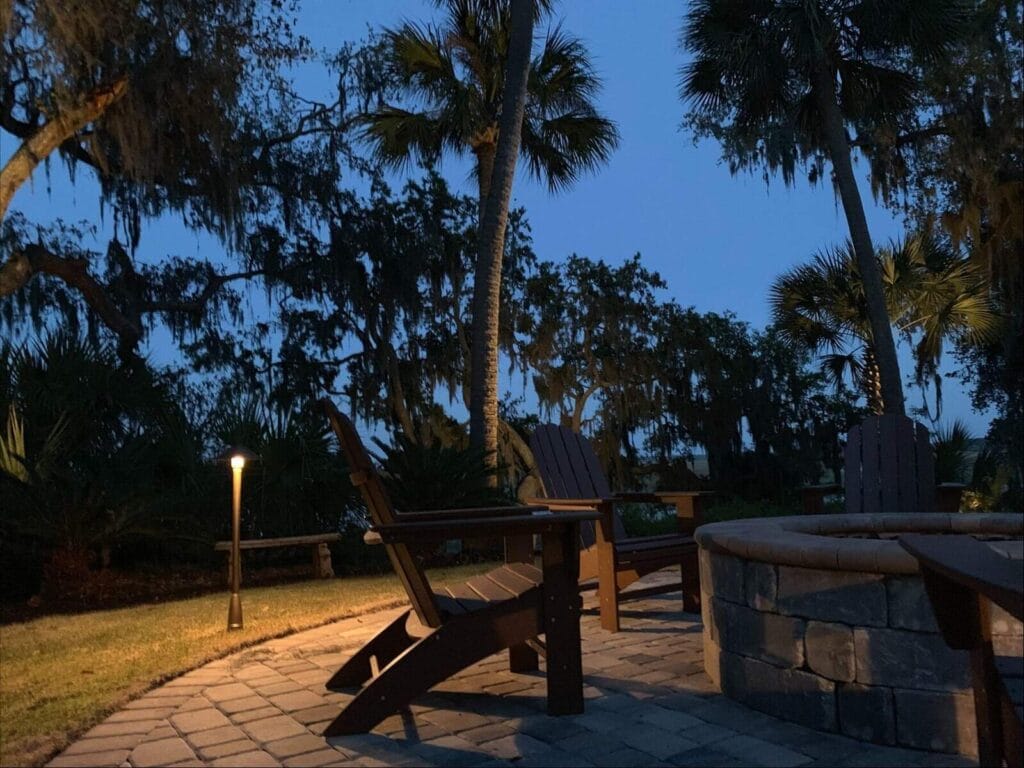 Outdoor patio lighting with warm LED lamps highlighting seating and fire pit area at dusk.