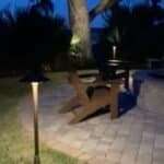 Outdoor lighting illuminating a tree and fire pit area for enhanced nighttime ambiance and safety.