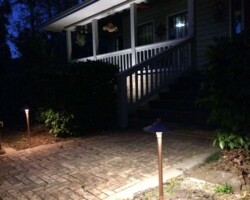 Premium outdoor lighting create a warm, safe atmosphere around this property in Bluffton, SC. Copper pathway lights illuminate the brick walkway at night in Bluffton, SC.