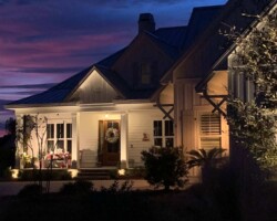 Soft lighting around the porch highlights decor and architecture on a charming home in the Hilton Head area. Beautiful nighttime exterior lighting in the Hilton Head area of South Carolina, enhancing house curb appeal and safety.