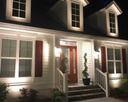 Nighttime outdoor lighting enhances curb appeal and safety for Hilton Head area residential properties. Brightly lit Hilton Head area home at night showcasing outdoor accent lights, upper level dormers, and beautifully illuminated front entrance.