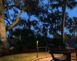 Enhancing outdoor ambiance with stylish lighting in a lush garden setting along the Broad River in the Hilton Head area. Beautiful backyard fire pit scene showcasing outdoor lighting with illuminating a paved patio area along the Broad River in the Hilton Head area.