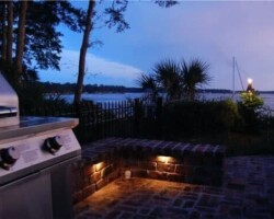 Luxurious outdoor patio lighting creates a cozy ambiance overlooking the May River of Bluffton SC at dusk. Beautiful outdoor kitchen patio with ambient LED lighting along the scenic May River in Bluffton, SC at dusk.