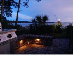 Luxurious outdoor patio lighting creates a cozy ambiance overlooking the May River of Bluffton SC at dusk. Beautiful outdoor kitchen patio with ambient LED lighting along the scenic May River in Bluffton, SC at dusk.